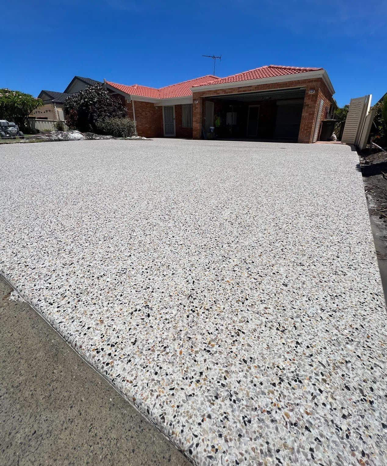 Exposed aggregate concrete driveway sweeping up to a double garage